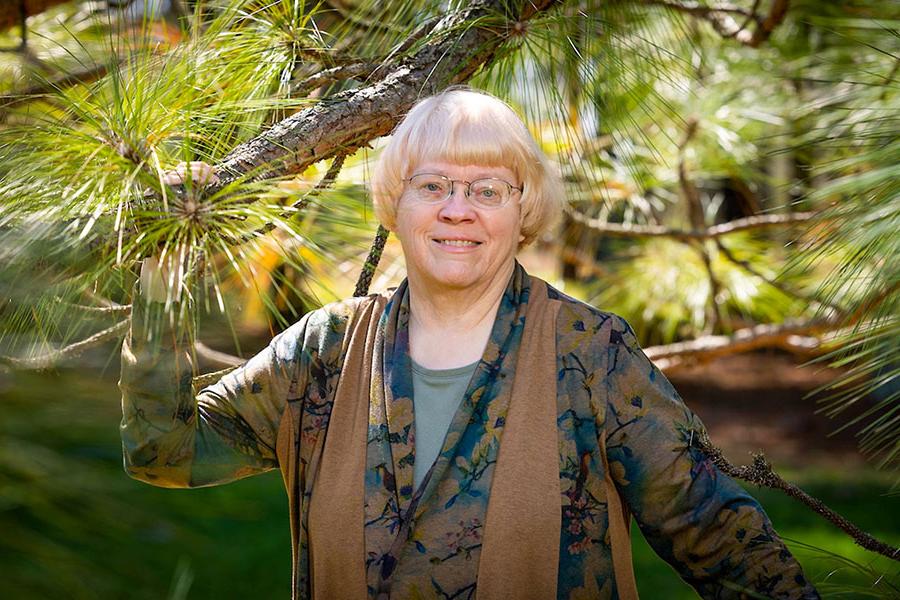 Dr. 去年夏天，在密苏里州斯特拉福德的洛维特松园，卡罗尔·米勒站在一棵长叶松旁. 在她40年的教学生涯中，米勒对环境法有着特殊的兴趣. (图片来源:Kevin White /密苏里州立大学)